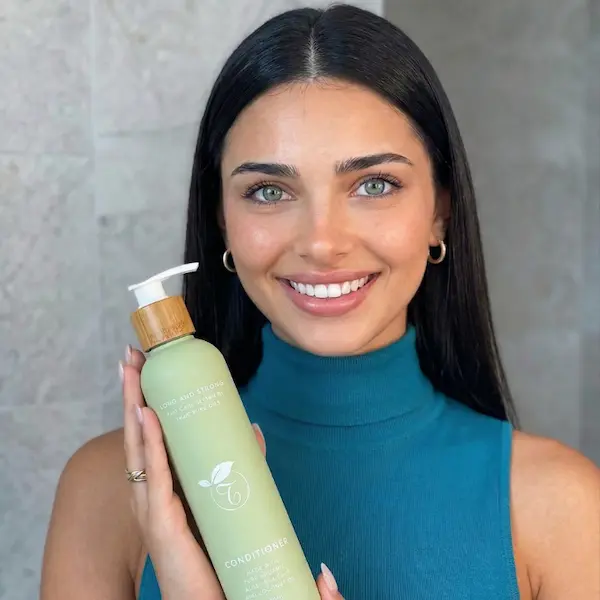 Photo of woman holding a green bottle of shampoo from Tasic Pure Oils